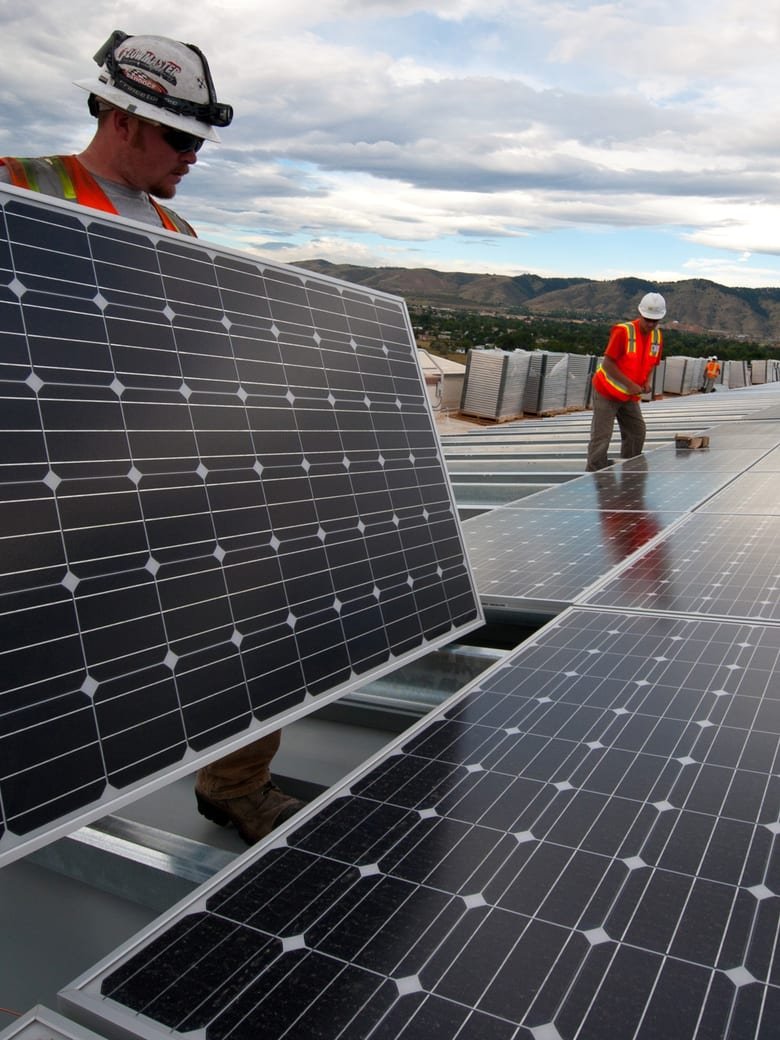 Equipe instalando módulos fotovoltaicos em cobertura industrial
